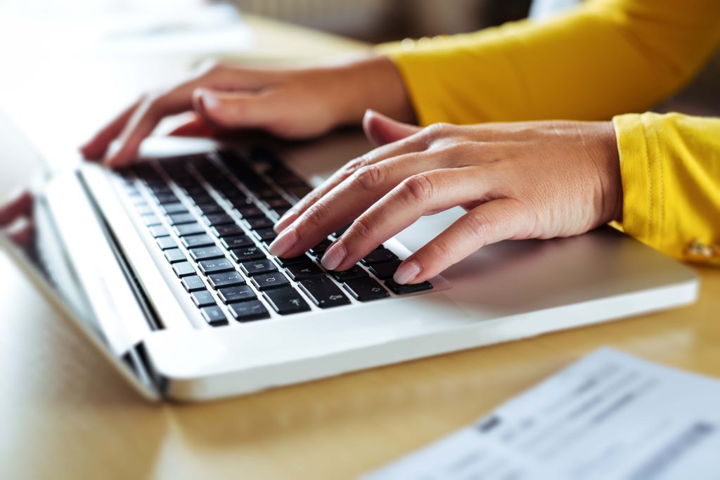 Hände einer Person auf der Tastatur eines Laptops als Symbol für die barrierefreie Nutzung digitaler Angebote.