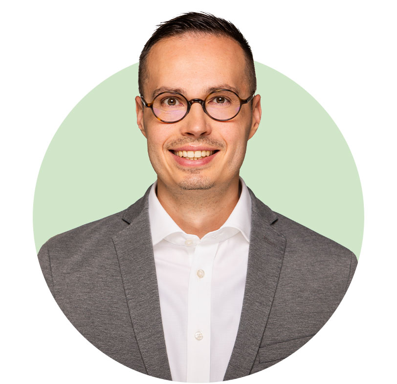 Portraitfoto von Rouven-Nagel: Ein Man mit runder Brille, hoher Stirn und braunen Haaren. Er trägt ein weißes Hemd und ein graues Jackett.
