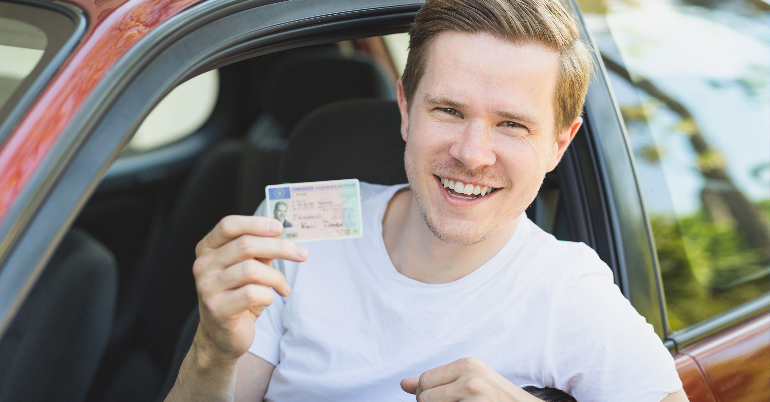 Mann im Auto mit einem Führerschein in der Hand