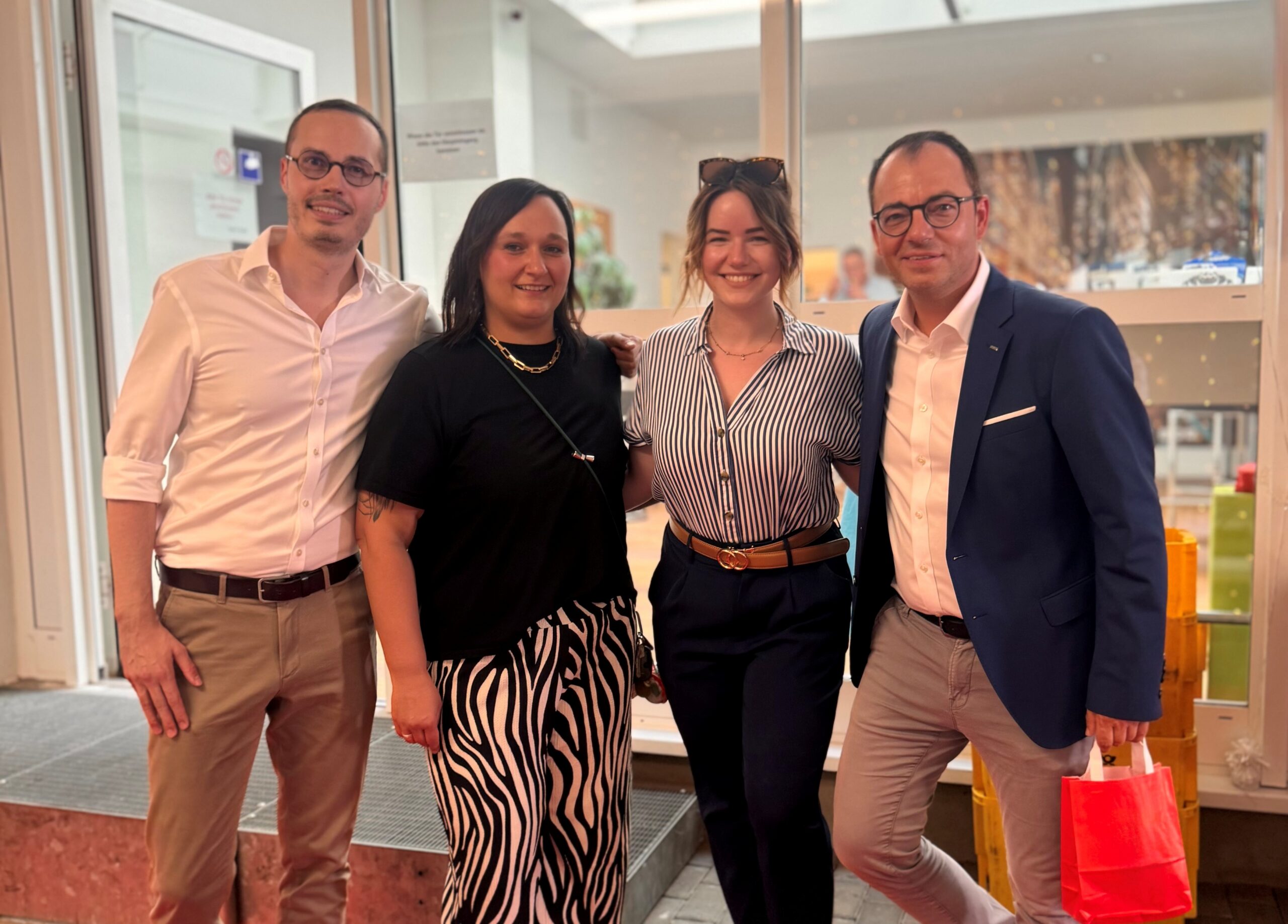 Gruppenbild mit zwei Männern und zwei Frauen in Business-Kleidung.