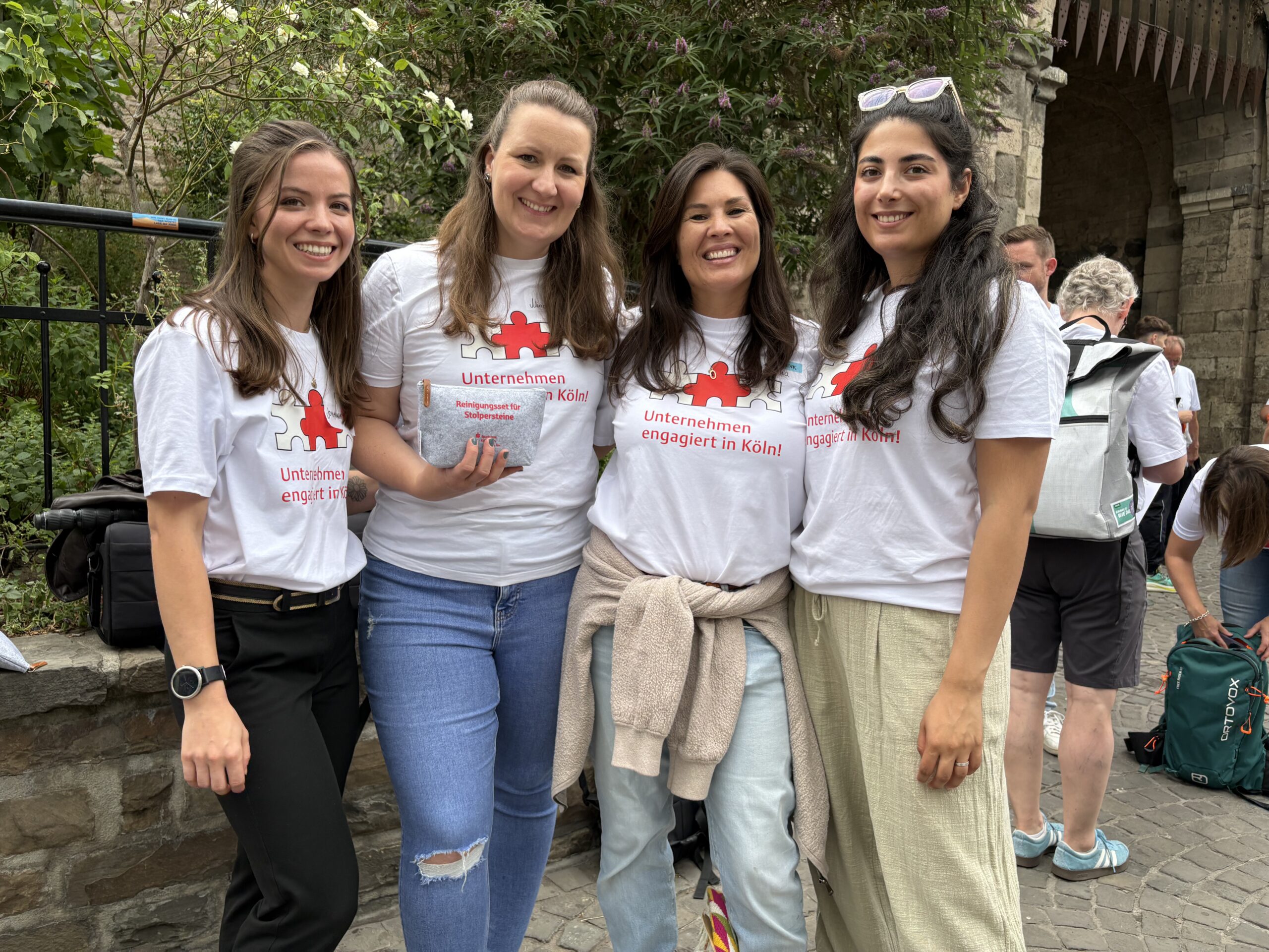 Gruppenbild mit vier DEVK-Mitarbeiterinnen während der Social Days in Köln. Alle haben braune, lange Haare und tragen das weiße T-Shirt zum Aktionstag.